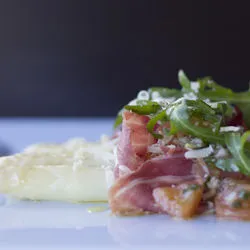 Een verfijnd voorgerecht met carpaccio en rucola op een bord.