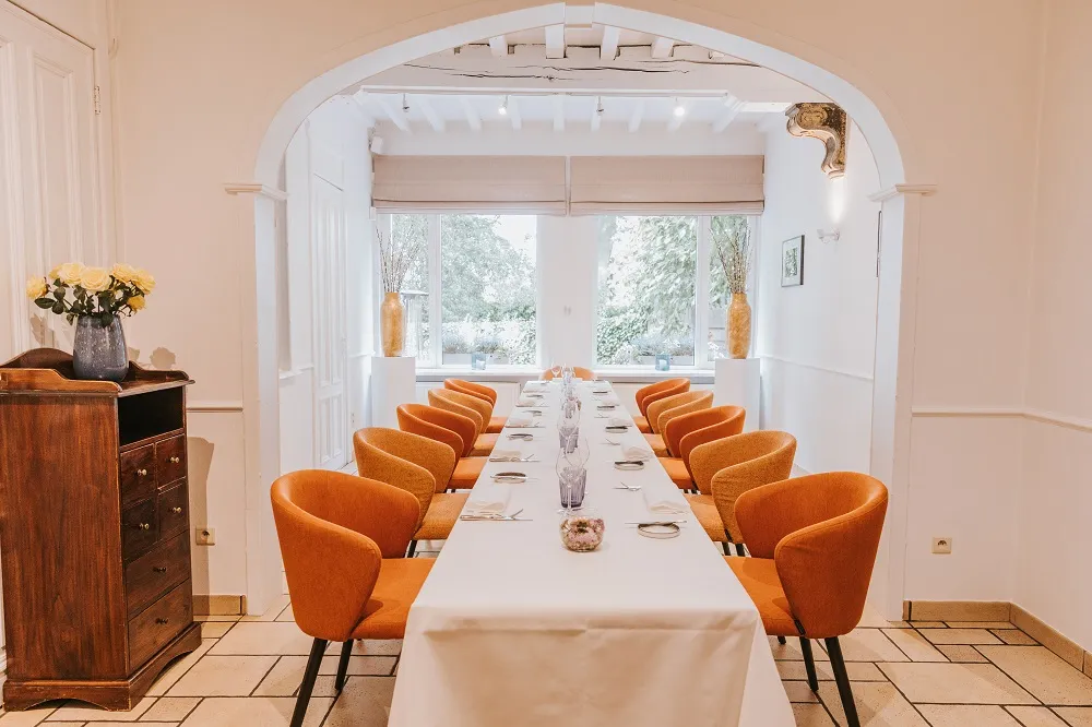 De eetzaal van 't Notenhof met gedekte tafels en uitzicht op de tuin.